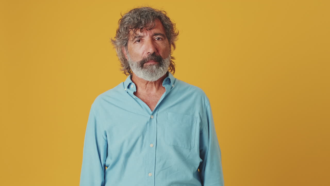 Mature Man Reacts with Shock and Surprise on Yellow Background