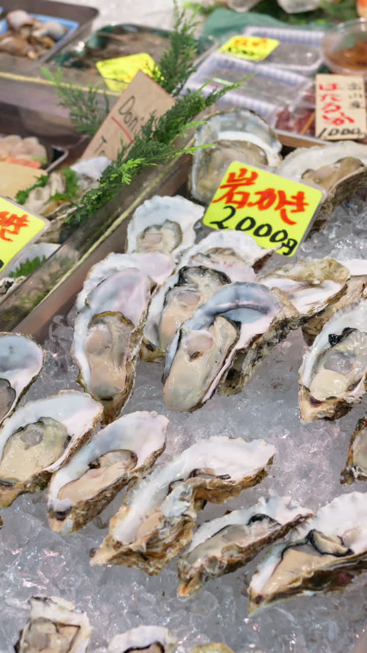 Close up of oysters on ice at the Tsukiji Fish Market in Japan. Vertical. Translation: "Produce descriptions"