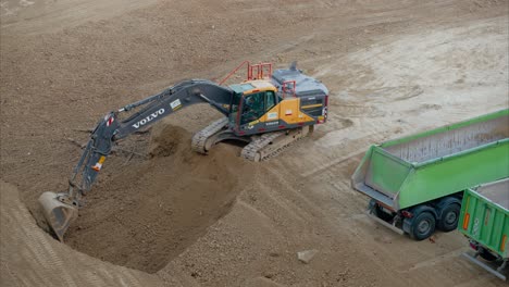 excavator digging a hole on active construction site while trucks are parked nearby. groundwork. digging the site to create trenches, foundations, or other necessary openings. site planning.