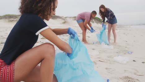 un grupo diverso de amigas que usan guantes de látex recogiendo basura de la playa