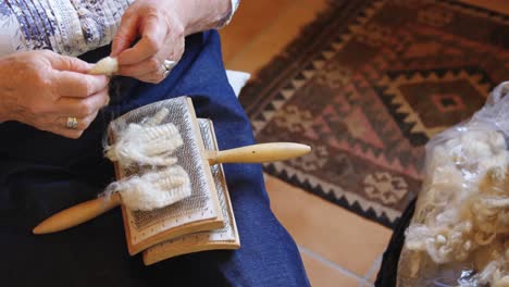 senior woman placing woollen yarn on brush 4k