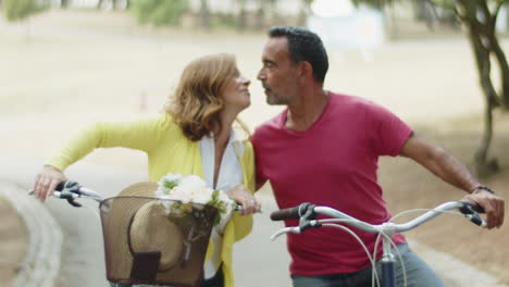 medium shot of caucasian couple sitting on bikes and kissing