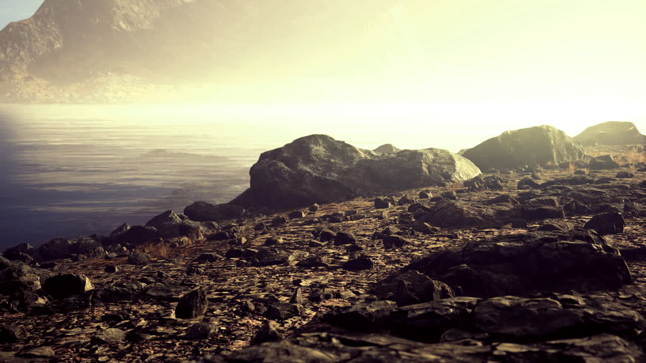 Quiet morning light illuminates rocky shoreline near serene water