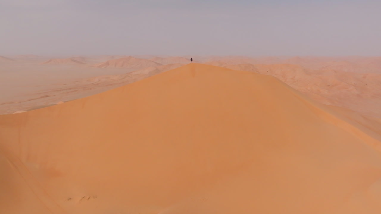 A person standing atop the highest dune in the Empty Quarters, Oman, summer