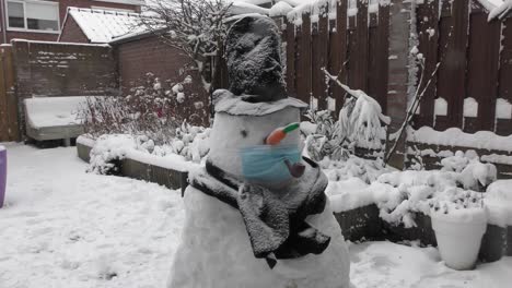 snowman with facemask and pipe in the backyard during winter season