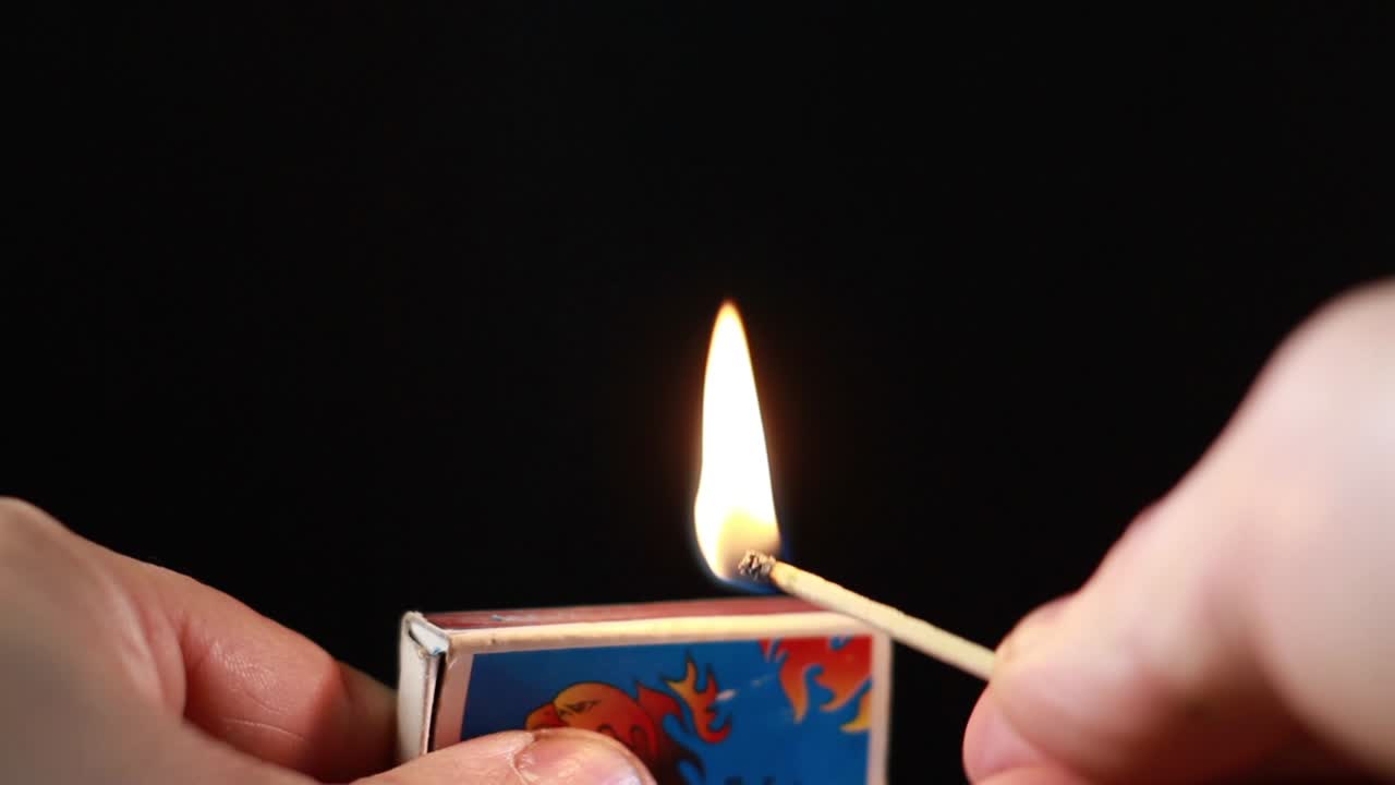 encendiendo un fósforo de matchbox sobre fondo negro