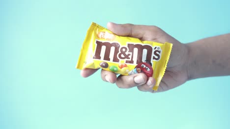 mano sosteniendo una bolsa de caramelos de chocolate de maní de m&m