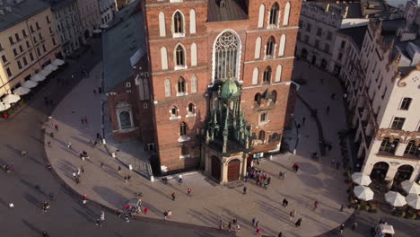 Vista-Aérea-De-Personas-Caminando-Frente-A-La-Basílica-De-Santa-María-En-Cracovia,-Polonia