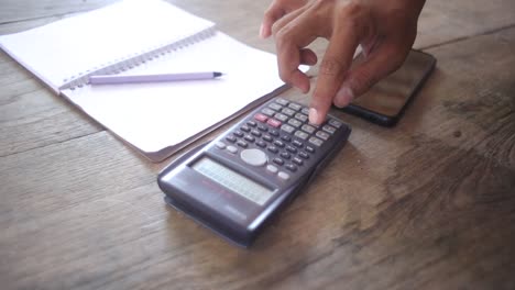 businesman's hands using calculator and financial data analyzing on wooden desk at the office