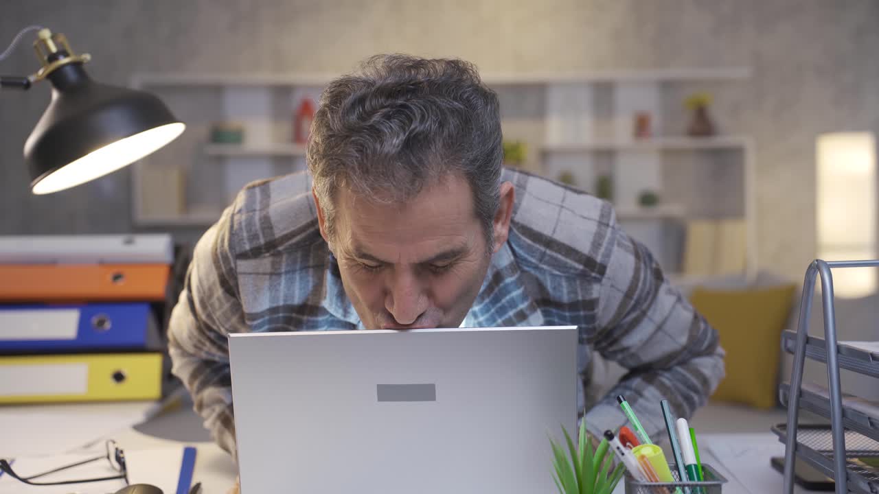 Mature man excitedly using laptop rejoicing and kissing laptop