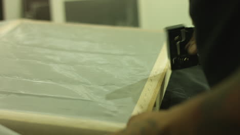 Side-Shot-Of-A-Man's-Hand-Adding-Staple-On-A-Silk-Screen-Frame