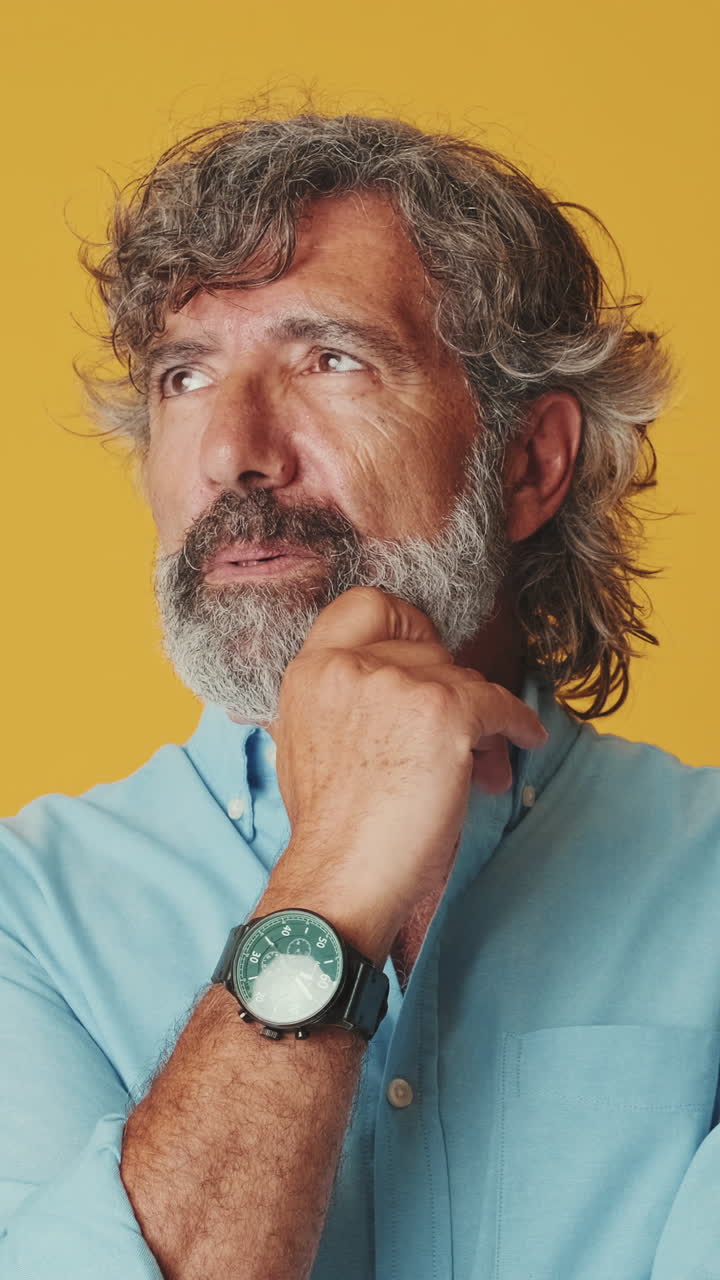 Thoughtful Mature Man Pondering and Looking Up Against Yellow Background