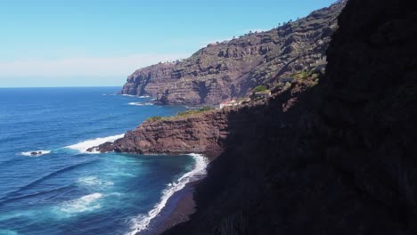 Wunderschöne-Küstenlandschaft,-Blaue-Meereswellen-Mit-Grünen-Palmen-Auf-Hohen-Klippen-Auf-Teneriffa-An-Sonnigen-Tagen,-Luftaufnahmen