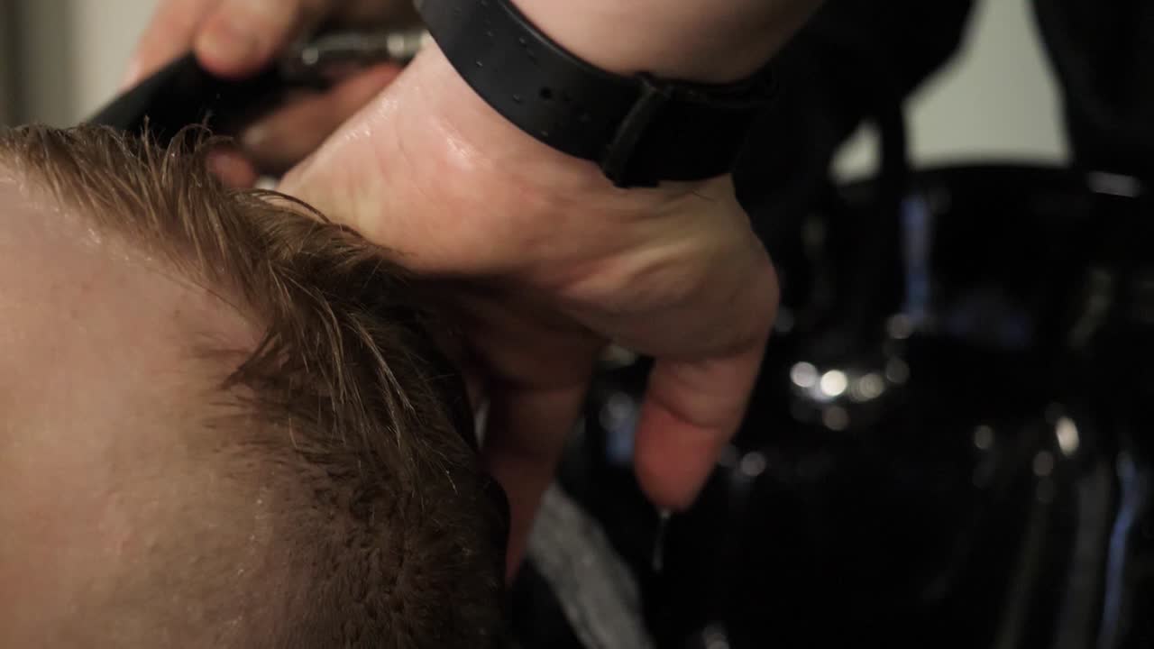 hombre recibiendo un corte de pelo y lavado de pelo en una barbería
