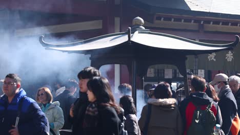 crowd participating in a smoke ritual at a temple