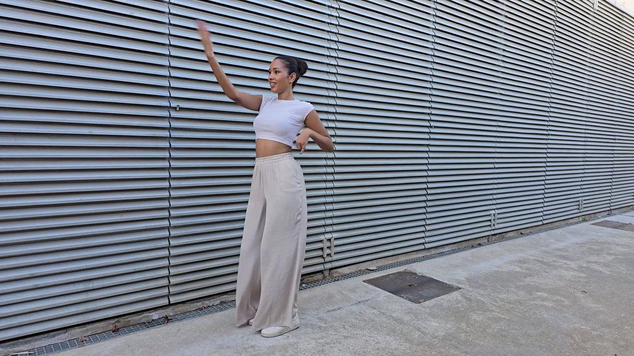 Una giovane donna alla moda che posa elegantemente contro uno sfondo architettonico moderno.