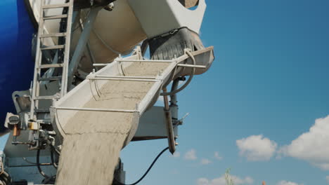 delivery of finished factory concrete concrete flows through a gutter from a mixer against a blue sk