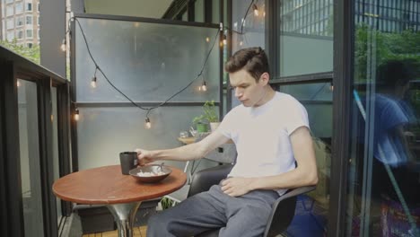 portrait of a young caucasian man eating breakfast at the veranda