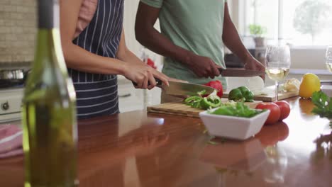 Midsection-of-biracial-couple-cooking-together,-cutting-vegetables