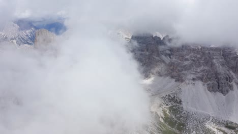 aerial flight through dense clouds and rocky mountains in background - tre cime di lavaredo towers