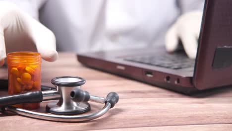 médico trabajando en una computadora portátil con suministros médicos