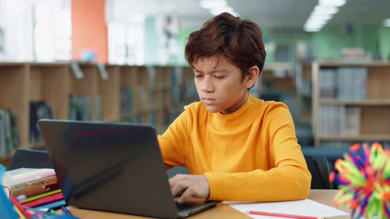 Boy using a laptop in a library