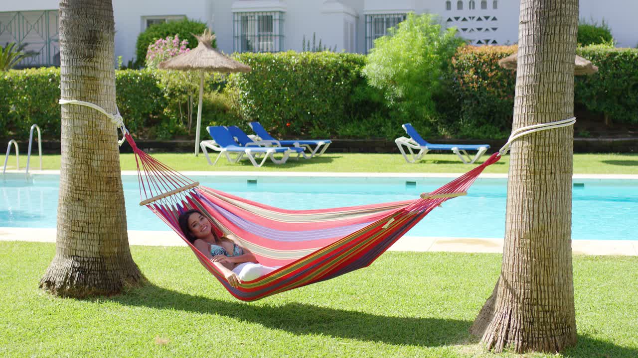 mujer en hamaca en un complejo tropical con piscina
