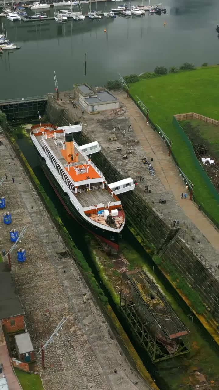 Right-to-left travelling social ratio aerial video of the SS Nomadic at Titanic Belfast in Northern Ireland, UK. Produced in 1080x1920, 60FPS and with Rec709 color
