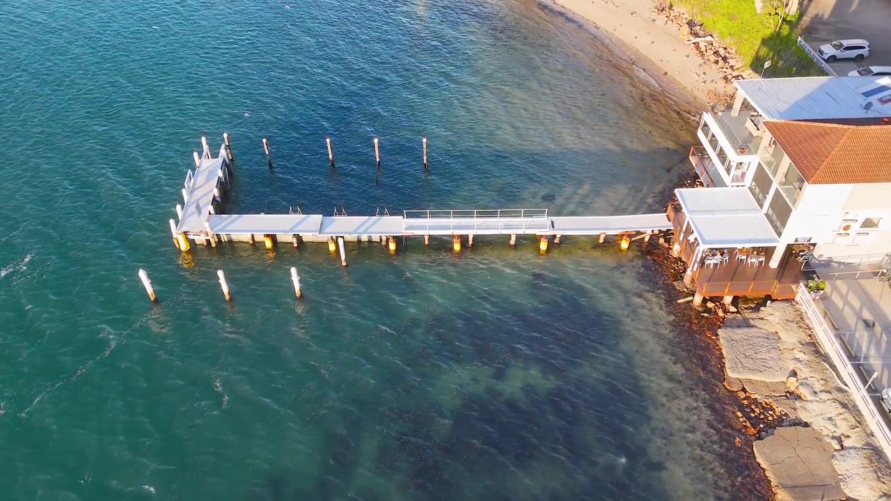 Ripresa aerea dall'alto di un molo in legno e un edificio lungo la costa di Nelson Bay