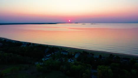 Vista-Aérea-Por-Drones-De-La-Puesta-De-Sol-Sobre-Casas-De-Playa-Con-Coloridos-Reflejos-De-Las-Olas-Del-Océano-Y-Casas-De-Vacaciones-A-Lo-Largo-De-La-Costa-Atlántica-De-Nueva-Inglaterra