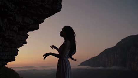 woman in silhouette at sunrise by a cave