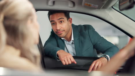 car salesman talking to customer inside vehicle