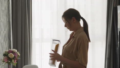 young female looks at spaghetti in tall container in kitchen