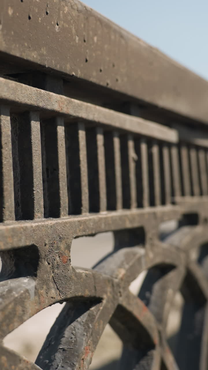 Close-up view of a weathered metal fence bridge with cars passing with speed on the bridge
