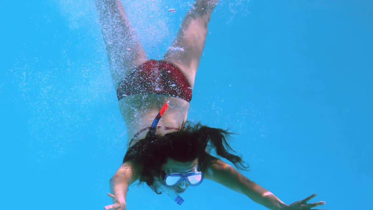Bruna felice sott'acqua in piscina con lo snorkel