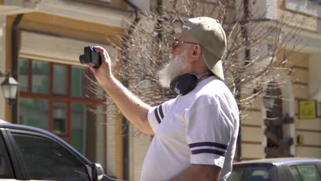 senior man in sunglasses and cap walk in the city and take pictures of sights