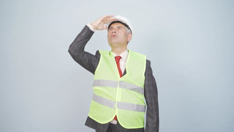 Looking-up,-the-engineer-is-holding-his-hard-hat.