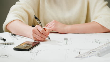 architect or engineer working on blueprints with calculator