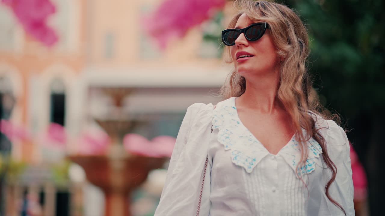Woman walking under rows of pink umbrellas above the streets of the old town of Grasse, France