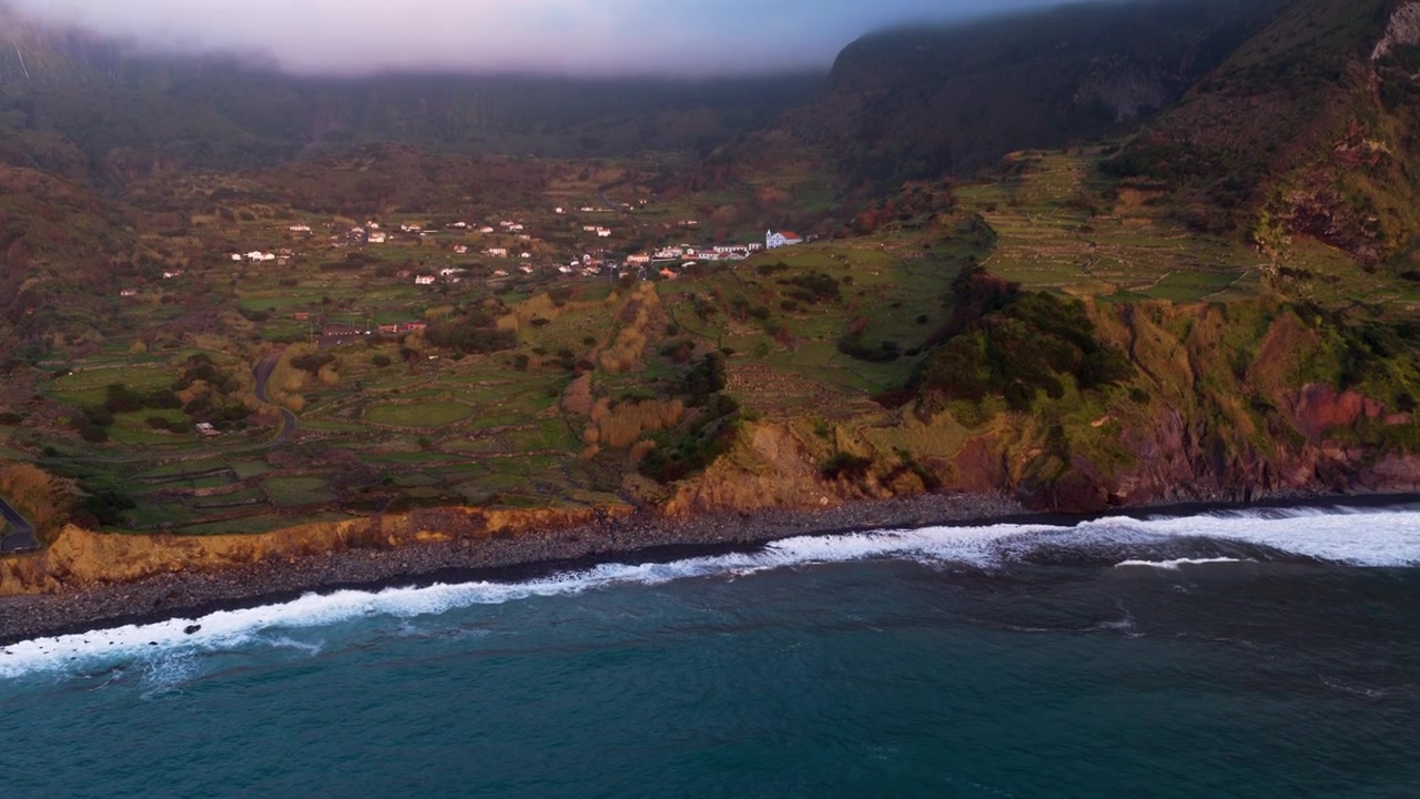 Onde si infrangono contro la costa di ciottoli vicino al villaggio costiero di Fajãzinha sull'isola di Flores nelle Azzorre, Portogallo. Ripresa aerea