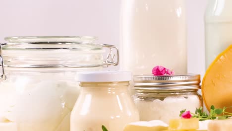 a variety of cheeses and dairy bottles arranged with herbs on a light background.