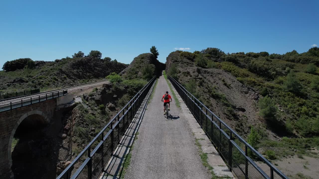 ciclista cruzando un viejo puente ferroviario en un espléndido día de primavera montando un btt