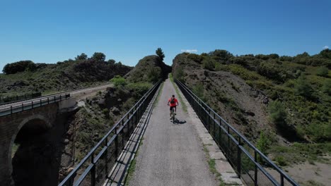 Biker,-Der-An-Einem-Herrlichen-Frühlingstag-Auf-Einem-BTT-Eine-Alte-Eisenbahnbrücke-überquert