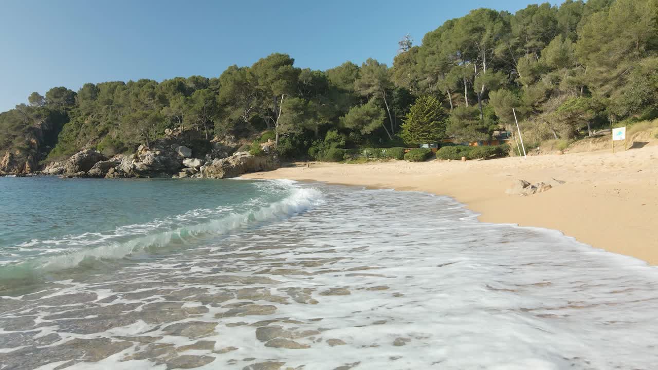 Onde che si infrangono dolcemente sulla sabbia di una spiaggia deserta in Spagna