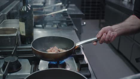 el cocinero está balanceando ambas sartenes en la cocina