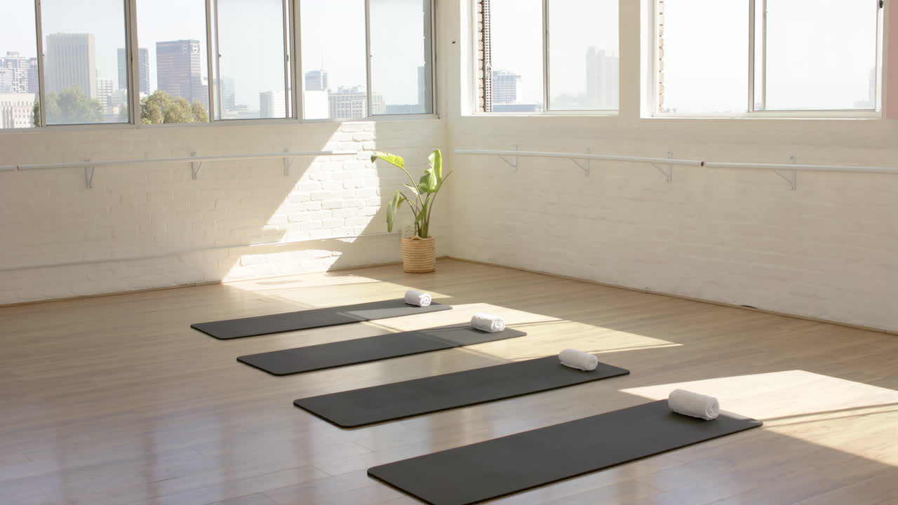 A bright yoga studio shows mats and towels neatly arranged for class