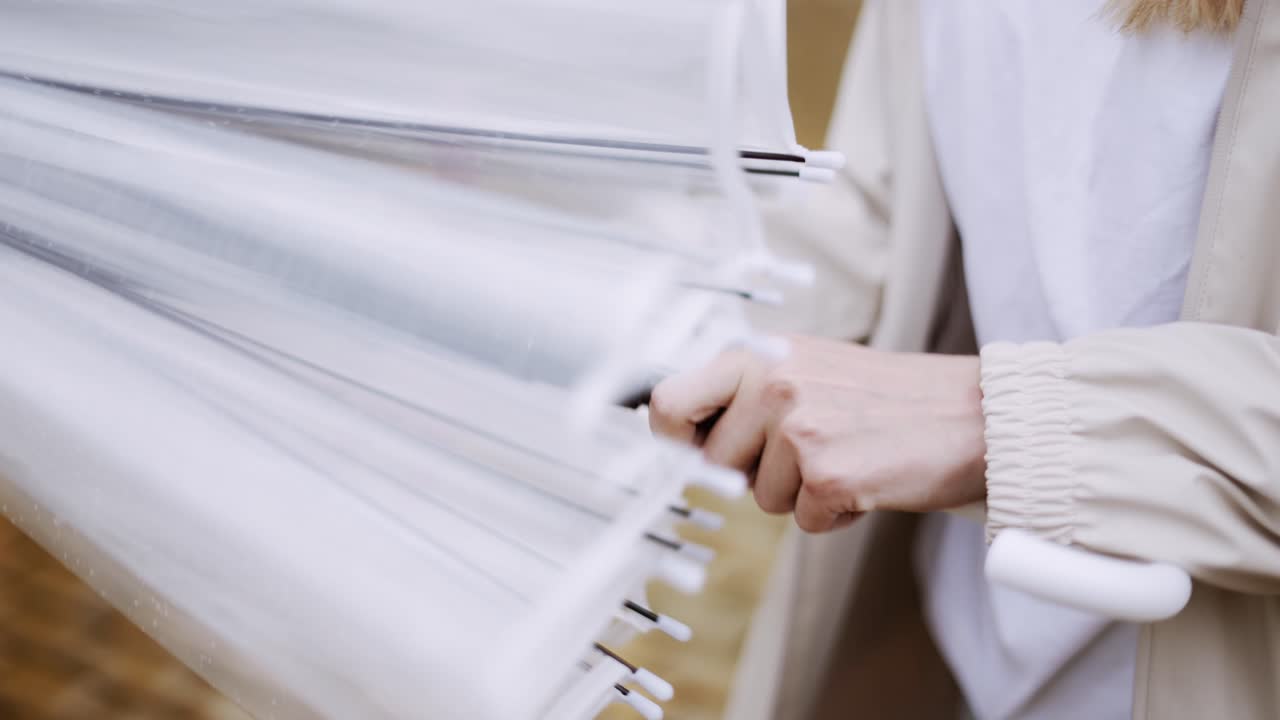 молодая женщина закрывает прозрачный зонтик на открытом воздухе