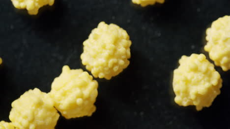 macro top shot of yellow cells moving on a black surface. surface spinning clockwise. virus cells moving through the frame