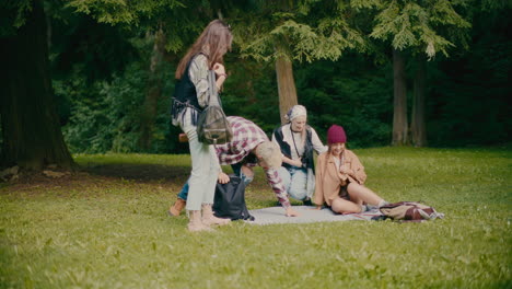 Happy-Friends-Sitting-On-Blanket-In-Park