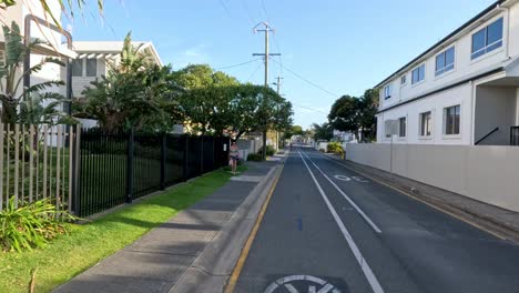 a quiet suburban road with passing cars and pedestrians